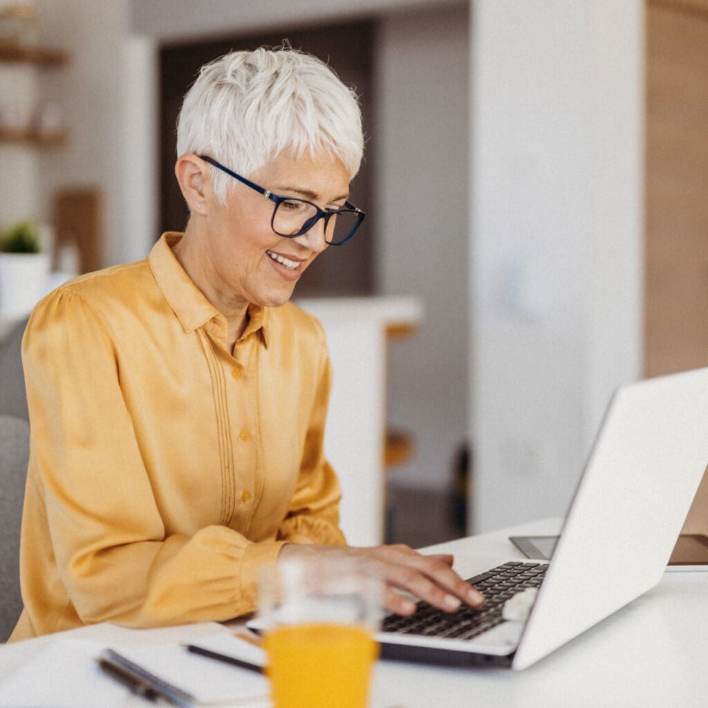 Woman at home engaged with her laptop smiling