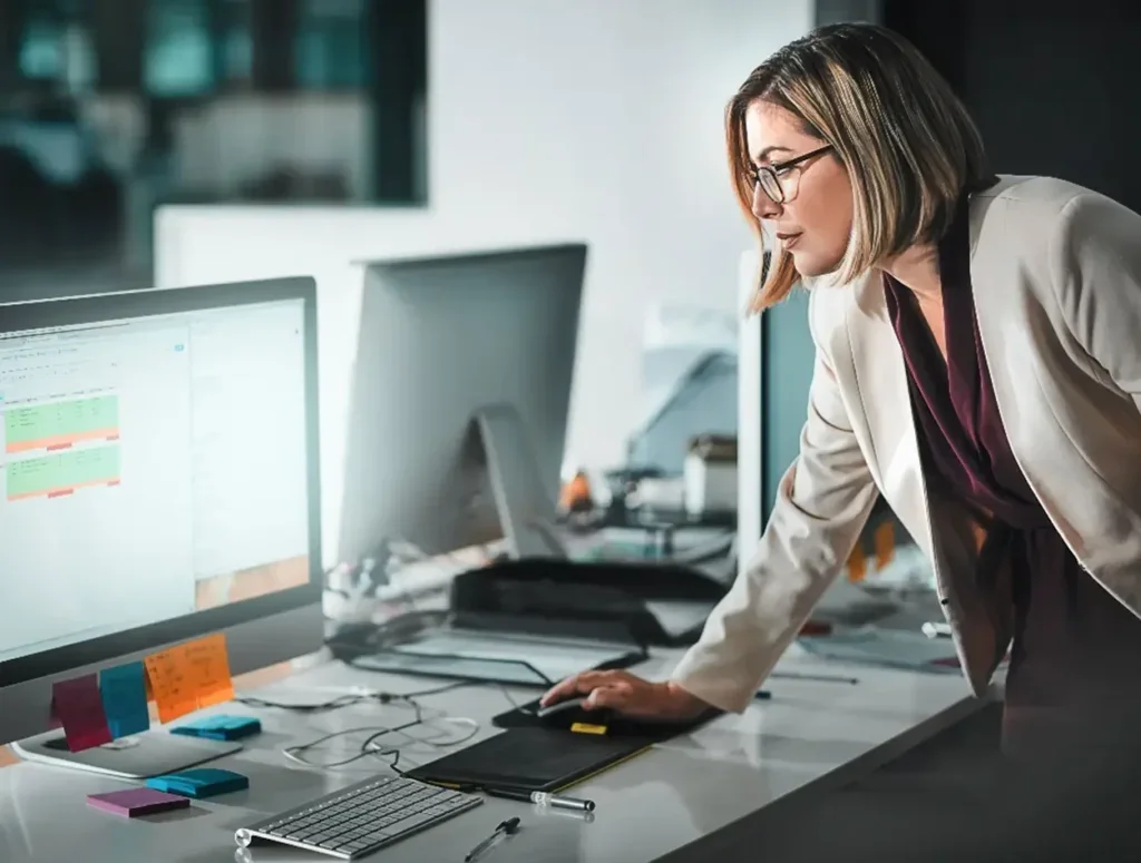 A woman leaning over and working on her computer.